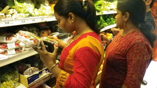 インドのスーパーマーケットにて、目新しい果物・イチゴを手に取る女性
